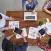 persone sedute attorno a un tavolo con note, tablet e pc