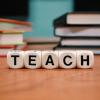 scrivania con libri e dadi con la parola "teach"